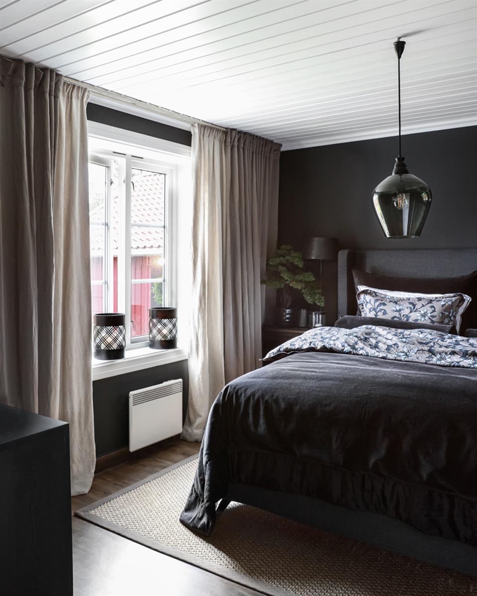 Halvor Bakke's soverom med oppredd dobbelseng, dobbel gardinskinne og to lag med gardiner. Foto.